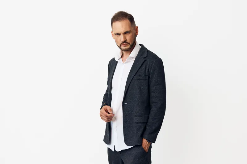Professional businessman stands in a confident pose, wearing a tailored suit against an isolated white background, conveying focus, determination, and calm authority.