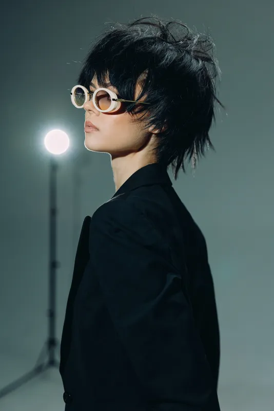 Stylish woman with sunglasses and black outfit in studio with moody lighting and artistic vibe