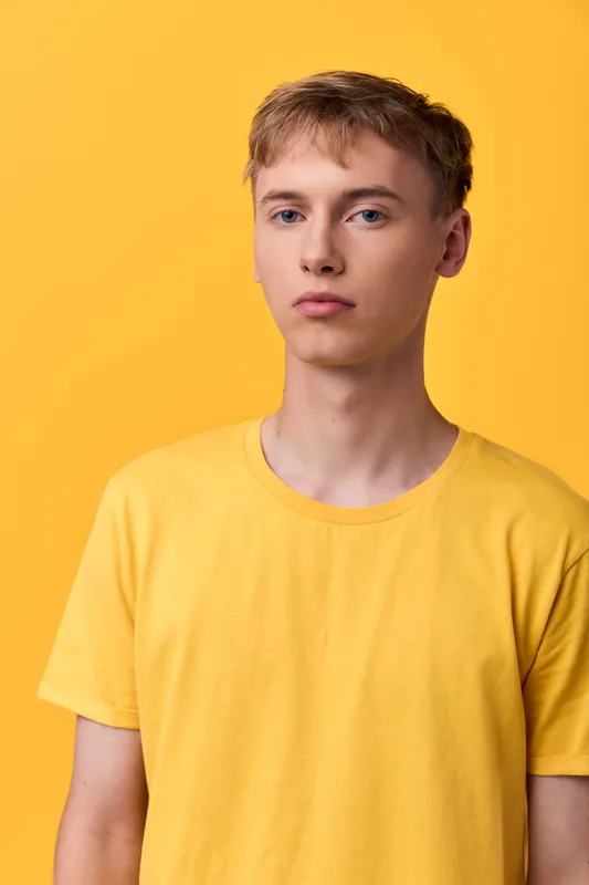 Yellow themed image showing a young man in a plain yellow tee against a solid yellow background, conveying casual fashion and clean studio style suitable for advertising campaigns