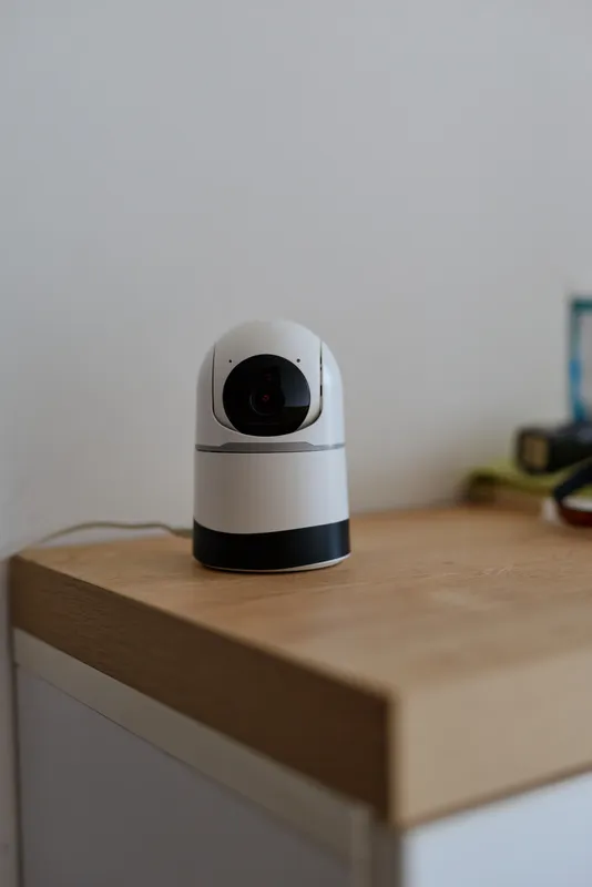 Indoor home camera on a desk, a compact security device in a calm, sunlit room, capturing everyday life with minimal decor, clean lines, and subtle tech presence for modern monitoring