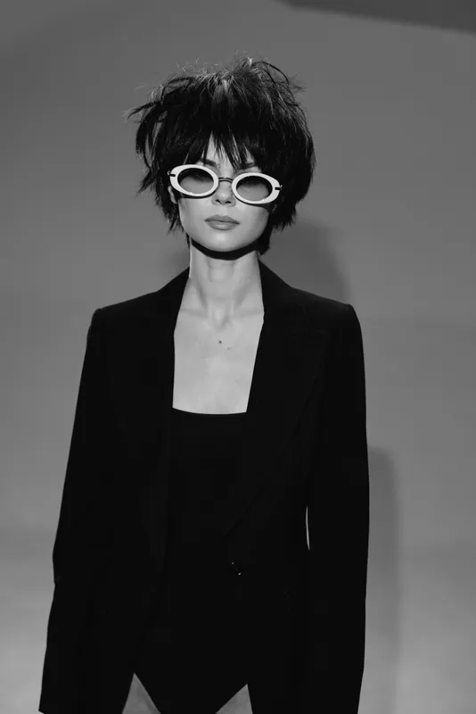 Stylish woman with sunglasses and black blazer in a black and white portrait.