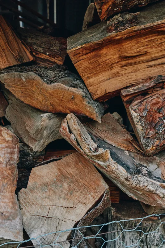 Wood pile, firewood, logs, stacked firewood, rustic: close-up of split hardwood stacked at a rural cabin, textured bark and grain, autumn atmosphere for fireplace, heating and cozy lifestyle.