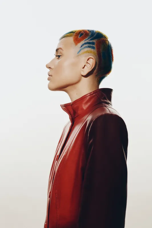 woman with colorful shaved hair in red leather jacket, side profile, creative hairstyle, modern fashion, studio lighting, white background, bold style