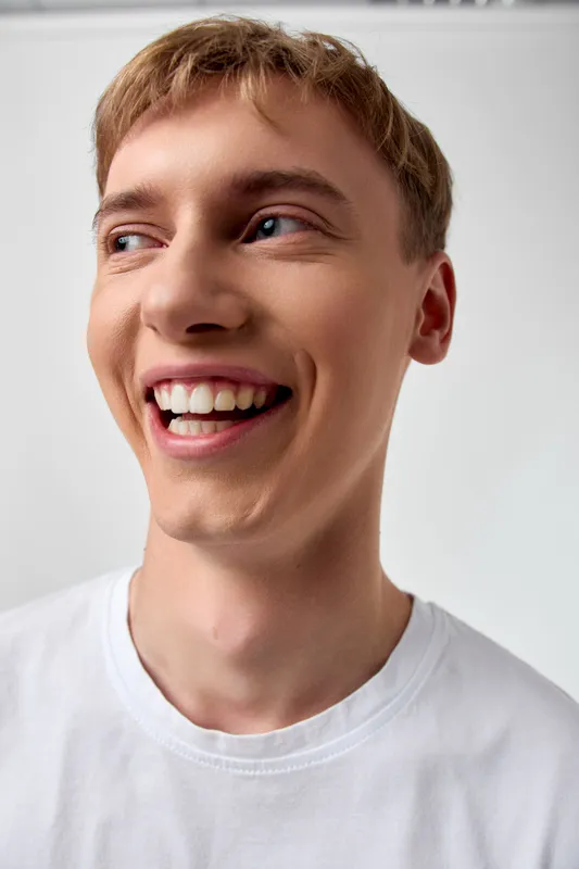 Smiling man in a white shirt with a bright joyful expression, candid shot capturing happiness, warmth, confidence, and a friendly, approachable mood suitable for lifestyle campaigns