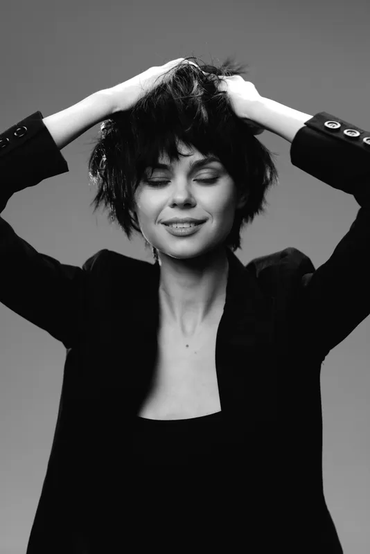 black and white smiling woman with short hair and blazer in studio