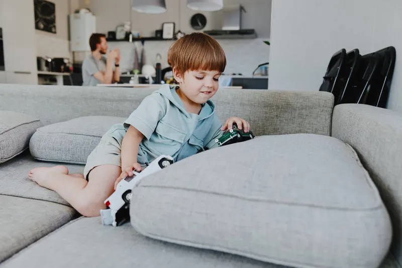 Joyful boy playing with toy cars in a cozy living room, engaging in imaginative play and enjoying quality time at home with family.