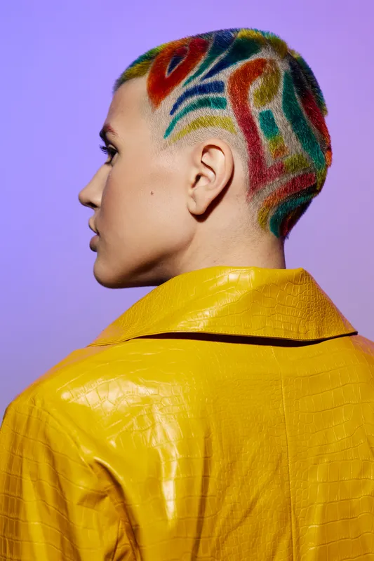 woman with colorful shaved hair and stylish yellow jacket, side profile, creative hairstyle with vibrant patterns on short hair, purple background
