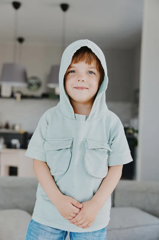 Smiling boy in a cozy sweater, showcasing joy and innocence in a bright living room setting filled with natural light and a welcoming atmosphere.