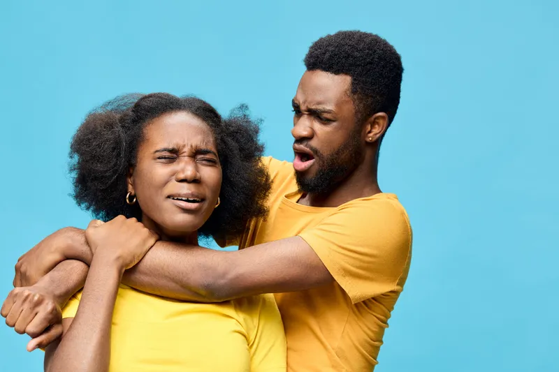 A couple expressing surprise and confusion against a bright blue background, wearing matching yellow t shirts, showcasing emotions in a playful moment
