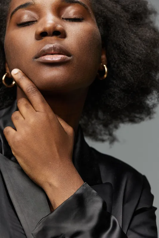 Confident African woman in a stylish black blazer, showcasing natural beauty and self assurance, perfect for concepts of empowerment and fashion