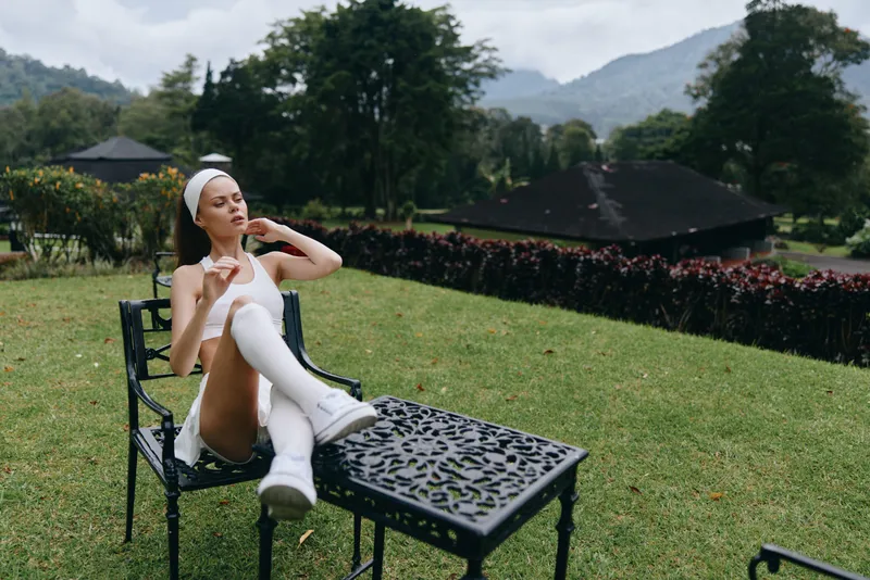 Young woman in elegant outfit relaxing outdoors, showcasing serenity with a natural backdrop, ideal for beauty, fashion, and wellness concepts