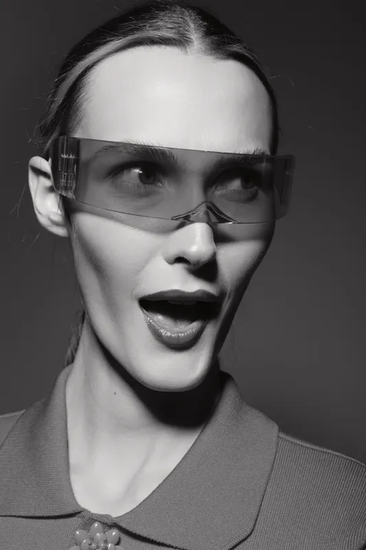 Portrait of a fair skinned Caucasian woman wearing transparent sunglasses with an open mouth expression. Studio shot in black and white with high contrast lighting.