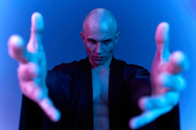 Captivating man reaching out with extended hands, exuding a mysterious aura in a unique lighting setup. Ideal for themes of magic and intrigue.