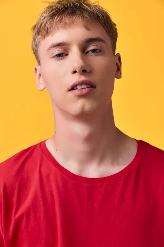 Man with a casual look wearing a red shirt against a bright yellow background, studio photography style, head and shoulders crop, vibrant mood, ready for advertising use