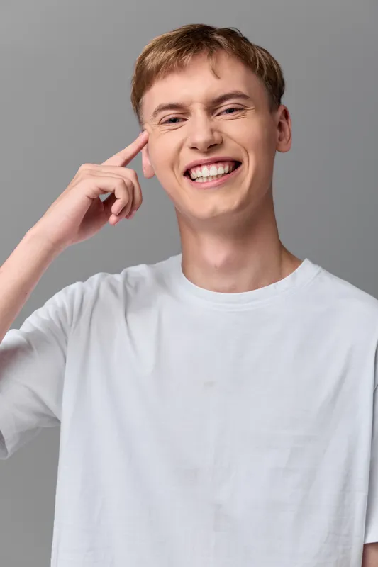 Thinking, man, smile, idea, head, casual, studio, confident, creative, expression, bright lighting, relaxed pose, white tee, modern stock photo depicting innovation and focus
