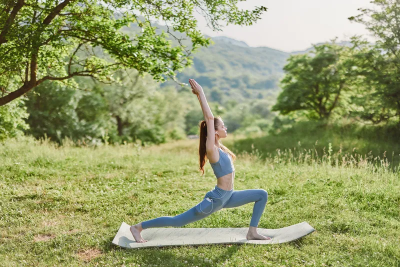 Young woman practicing yoga outdoors in a serene landscape, wearing sportswear, expressing calmness and focus, ideal for wellness and fitness themes