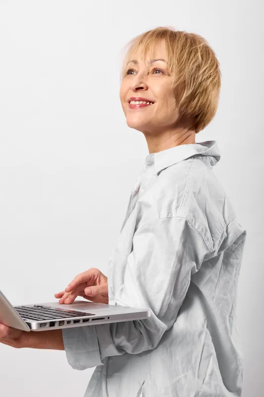 Woman with laptop typing, senior business technology smile in studio white background, cheerful professional working from home, focused portrait adult