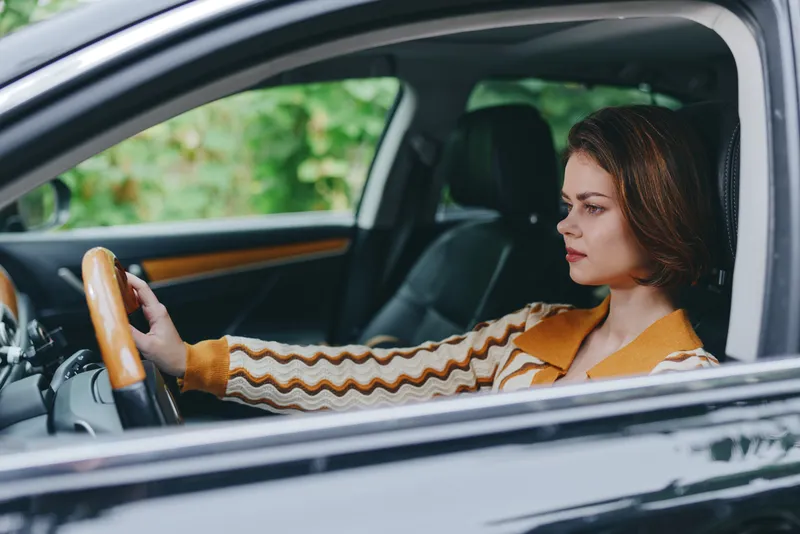 Car, driver, woman, smile a cheerful woman sits confidently in the driver's seat with her hand on the steering wheel, radiating joy and readiness for a journey.