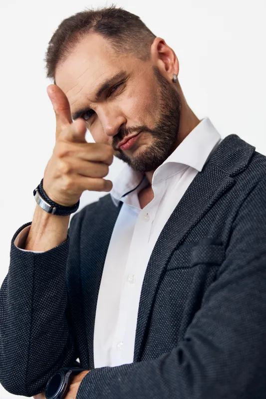 A confident business professional man poses with a pointed gesture against an isolated colorful background, conveying focus, leadership, and determination in a polished corporate mood.