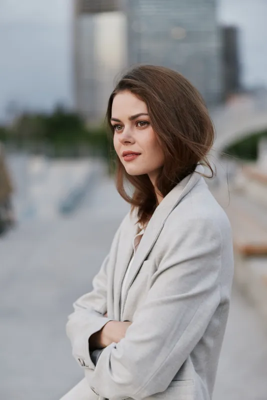 Business woman in a stylish light gray suit, exuding confidence and determination against an urban backdrop, showcasing a modern professional lifestyle.