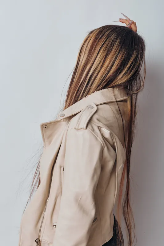 Woman, hairstyle, hair highlights and beige jacket with zipper standing against white background showing back, fashion and casual style for portrait and beauty concept.