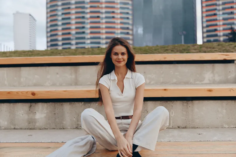 confident woman sitting casual urban outfit smiling relaxed modern city background fashion style