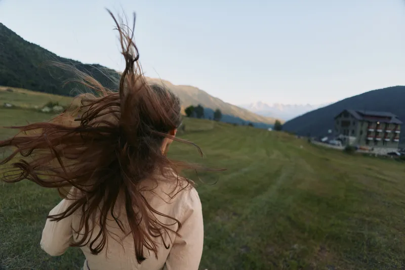 A woman lifestyle outdoor countryside field wind hair meadow portrait in a sunlit landscape. A dynamic, carefree moment capturing freedom, exploration, and connection with nature.