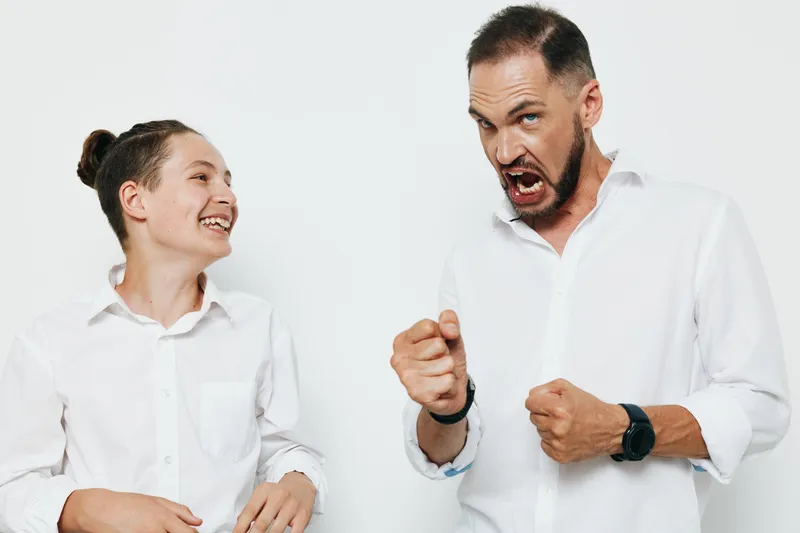 A professional business man expresses a strong emotion while engaging with a colleague, set against an isolated colored background, highlighting a dynamic moment of focus, energy, and determination