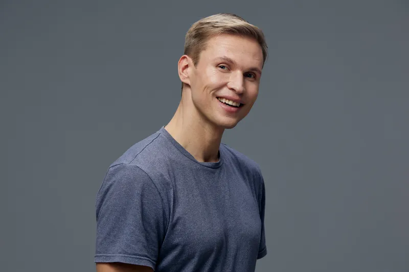 Smiling young caucasian man wear blue tshirt look camera isolated on grey background portrait digital nomad concept