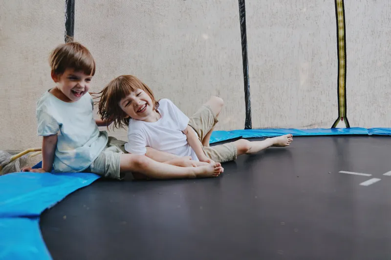 Smiling children enjoying a trampoline, showcasing joy and playful moments. The vibrant setting emphasizes their happiness and carefree nature, perfect for family themes.