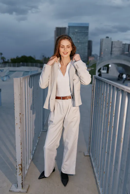 Confident businesswoman standing outdoors in a stylish suit with a modern city backdrop, radiating professionalism and elegance, showcasing a powerful presence.