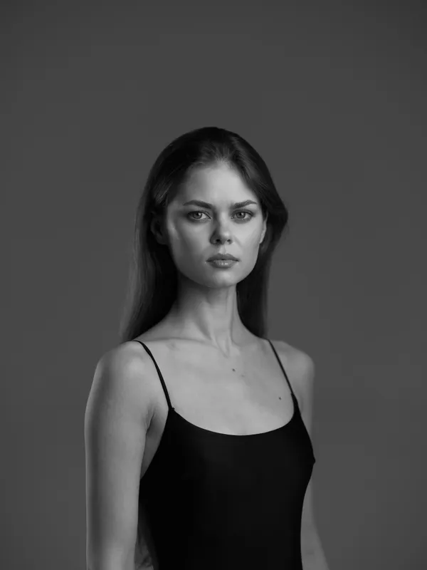 Black and white portrait of a serious woman with long hair in a dark top on a plain background