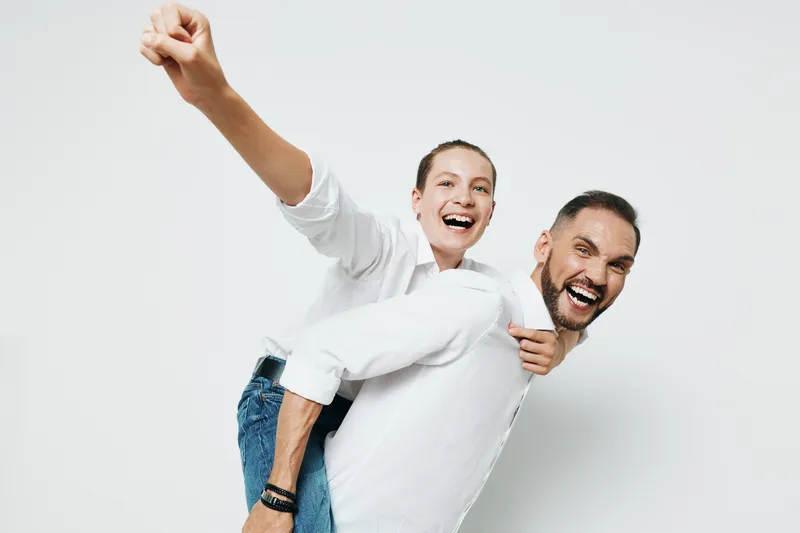 A professional man in business attire celebrates success with a colleague against an isolated white background, showing confidence, energy, and joy in a high-spirited corporate moment.