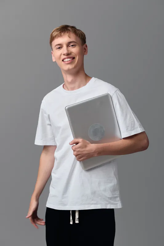 Smiling man in a white tshirt holds a laptop, casual study scene, ready for learning and lightweight work, friendly and professional for education content