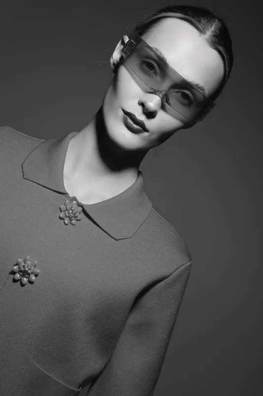 Elegant Caucasian woman with pale skin wearing futuristic glasses and vintage sweater. Studio portrait in black and white lighting, fashion and style concept.