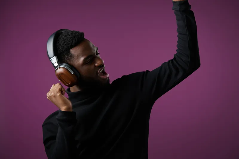 Young Black man enjoying music with headphones, dancing against a purple background, expressing joy and enthusiasm Perfect for lifestyle and music themes