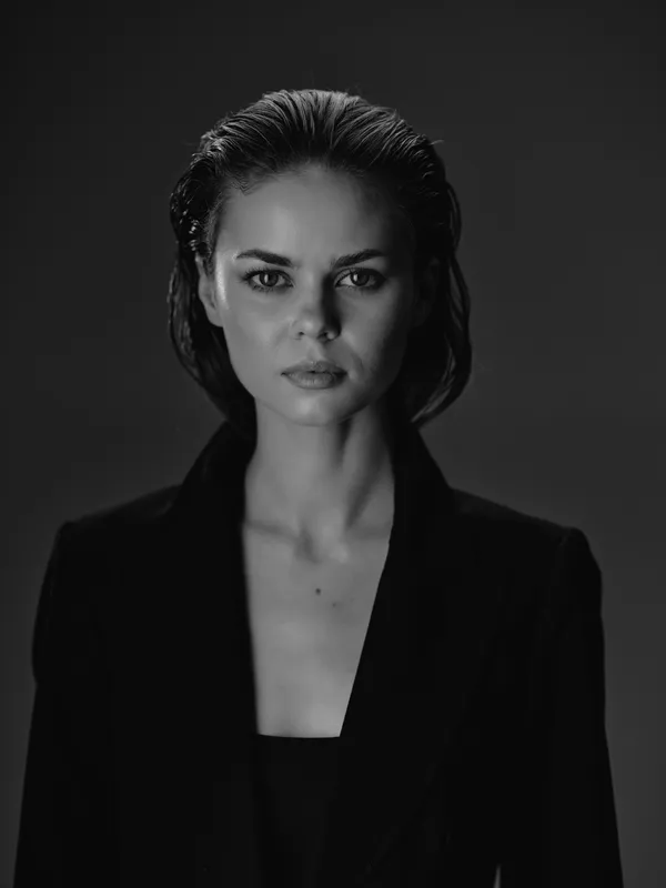 Black and white portrait of serious woman with wet hair wearing blazer in dark studio setting