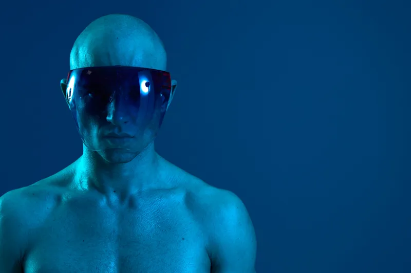 A striking image of a man with a futuristic look, wearing sunglasses and blue lighting to enhance the unique vibe. This photo combines modern aesthetics with bold colors.