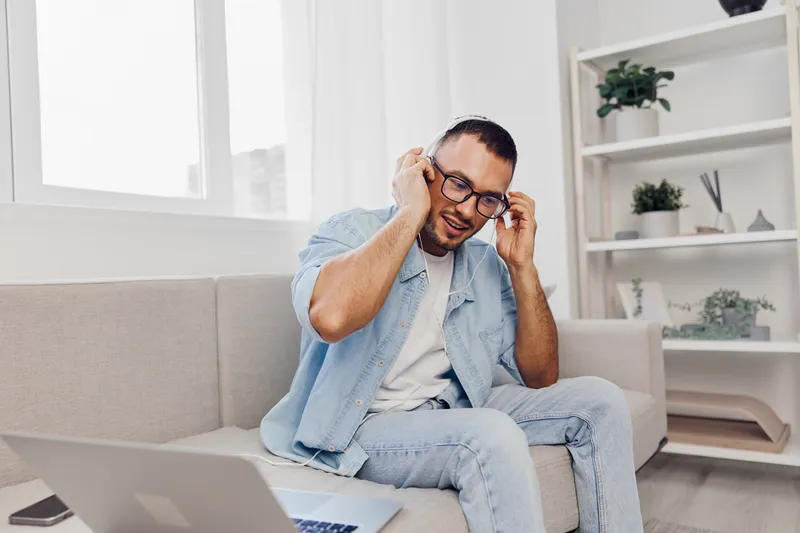A man experiencing AI anxiety sits on a couch with headphones, surrounded by a calming home environment, reflecting on his work-life balance and emotional health.