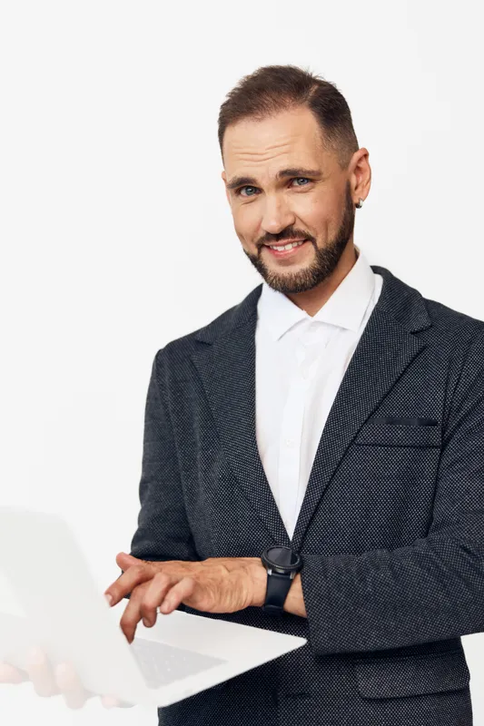 A man, business professional, stands with a laptop, projecting confidence and focus. An isolated colored background frames a calm, capable mood and strong readiness for action.