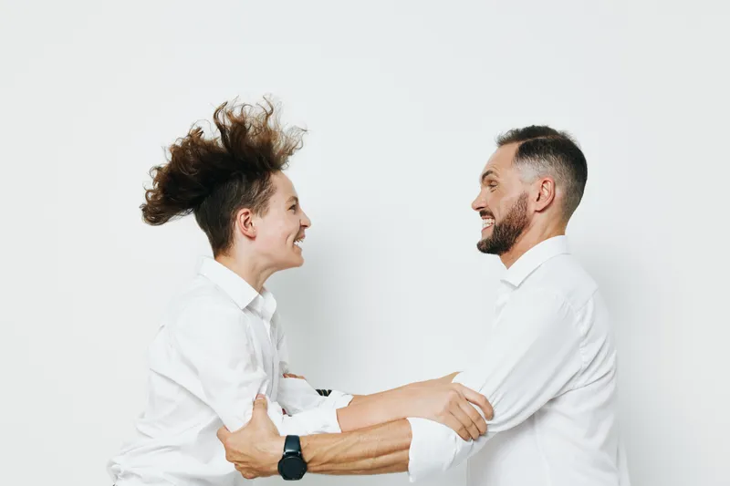 A business professional man and colleague share a warm moment, showing teamwork, confidence, and positive emotion against an isolated color background, conveying professional connection and