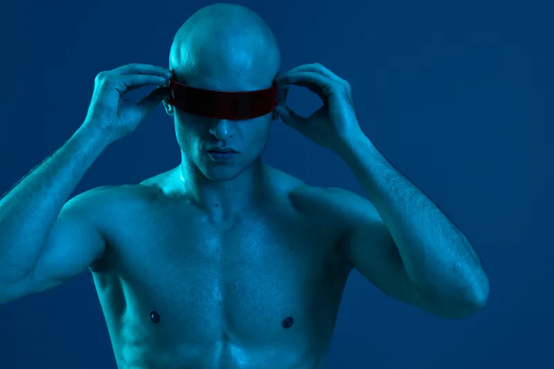 Strong man with futuristic sunglasses, showcasing innovation and style in a captivating blue light, embodying confidence and modernity.