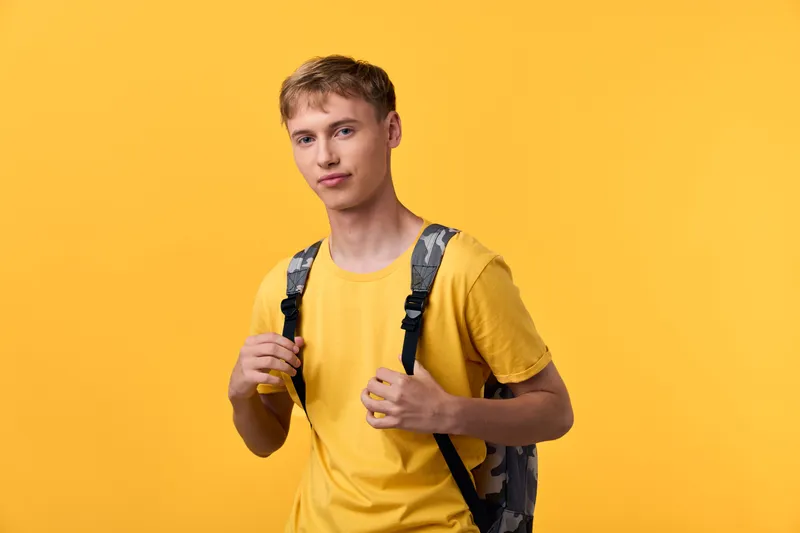 Student with backpack in a bright yellow studio, casual vibe, ready for class or adventures, capturing everyday youth energy and school life momentum today.