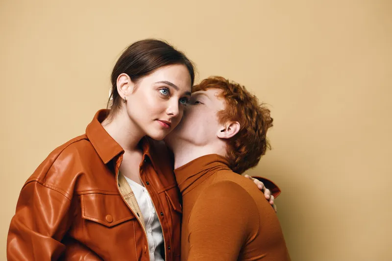 Couple, love, intimacy, and affection with woman and man in warm brown clothing embracing against beige background for romantic connection and emotional bond.