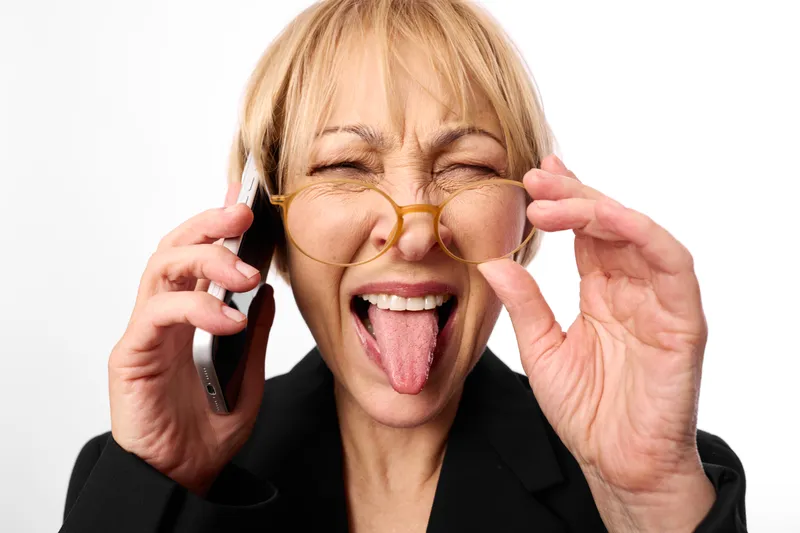 Cheerful woman portrait, glasses on face, laughing with tongue out, holding frames with hands, pretending to make a phone call, smartphone, white background