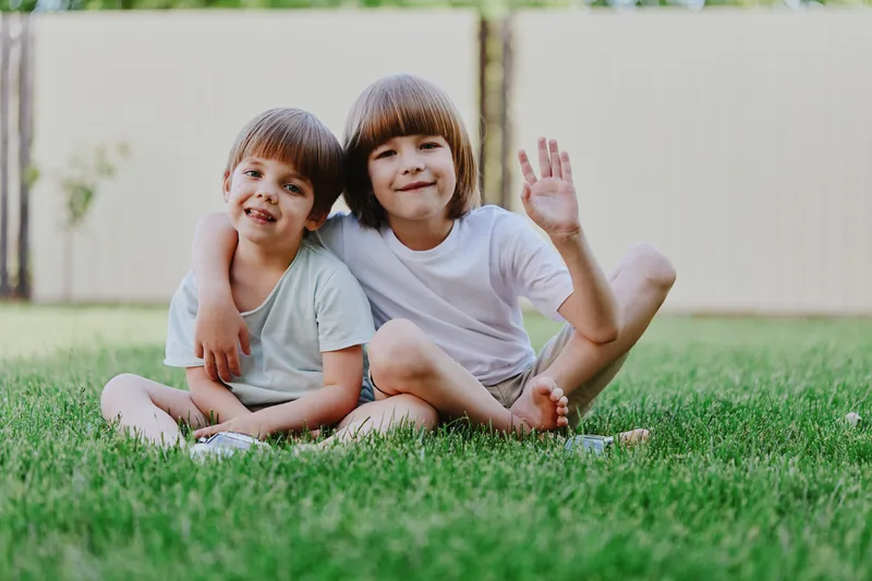 Two joyful boys playing outdoors on green grass, showcasing friendship and fun in a sunny environment, perfect for family-oriented themes and childhood moments.