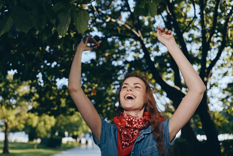 lifestyle woman enjoying summer outdoors in modern boho-western denim street style with a red bandana, vibrant film color capturing joyful energy and natural setting
