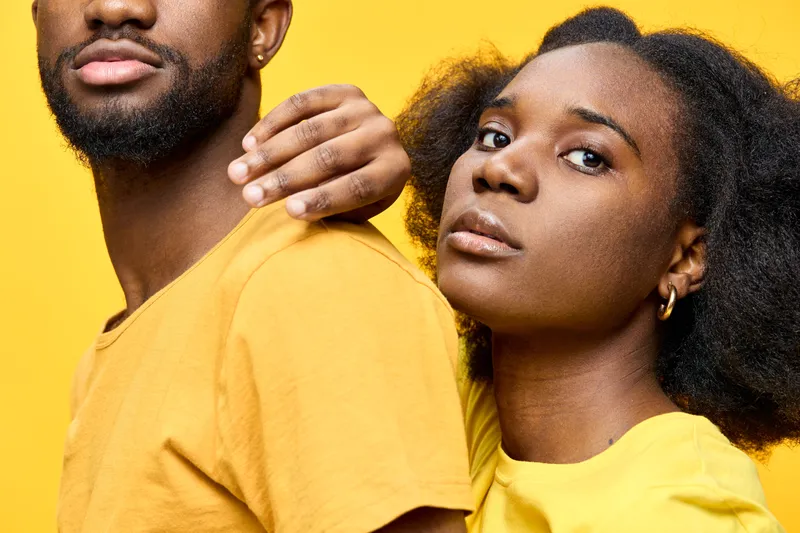 A portrait of a Black couple in matching yellow outfits against a bright yellow background, showcasing unity and confidence, ideal for themes of love and togetherness