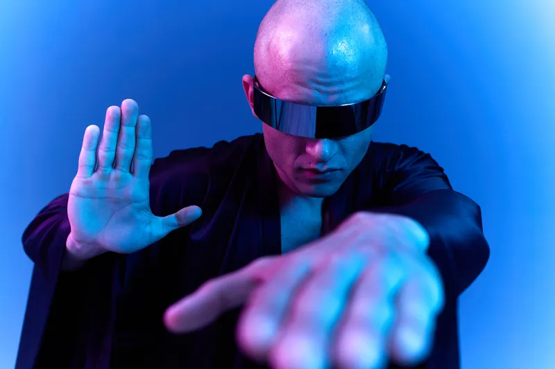 Confident man in futuristic attire exuding an aura of mystery with vivid blue lighting. Capturing a striking, modern vibe in a unique setting.