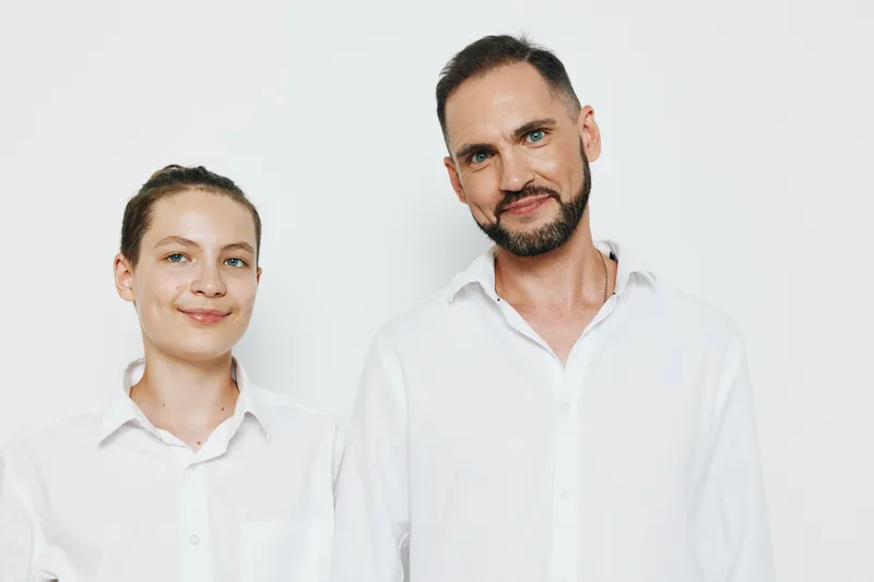 A professional man stands with a colleague against an isolated white background, showcasing business expertise, calm confidence, leadership, and collaborative spirit in a modern work setting.